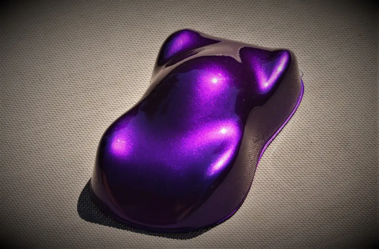 Próbka lakieru samochodowego w odcieniu **midnight purple**, lśniąca i metaliczna, na szarej powierzchni.