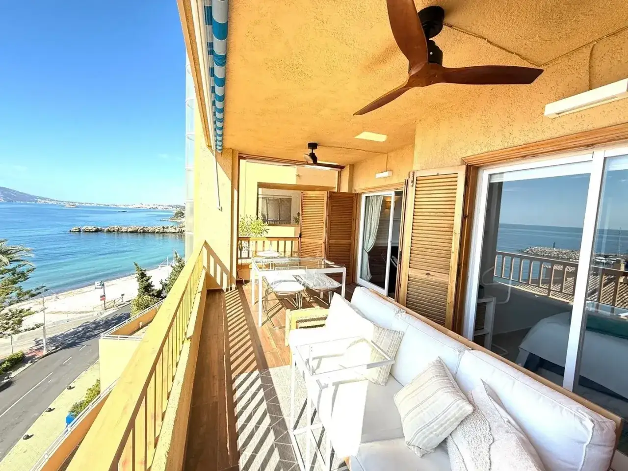 Balcon avec vue mer, parfait pour déménager en Espagne et profiter du soleil. Canapé blanc, table et chaises pour des repas en plein air.
