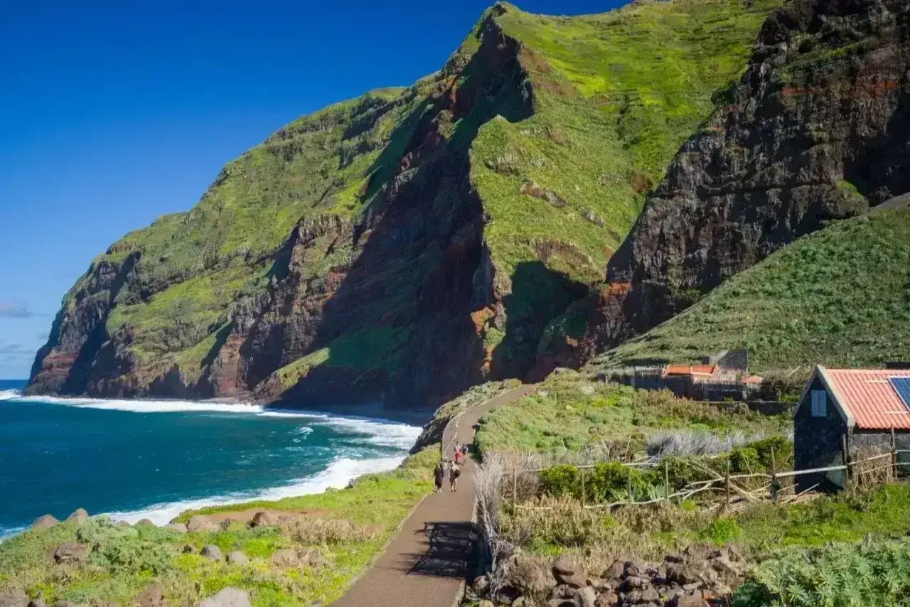 Wysokie, zielone klify Madery, wybrzeże z falami, ścieżka z turystami. Piękna madera pogoda listopad.