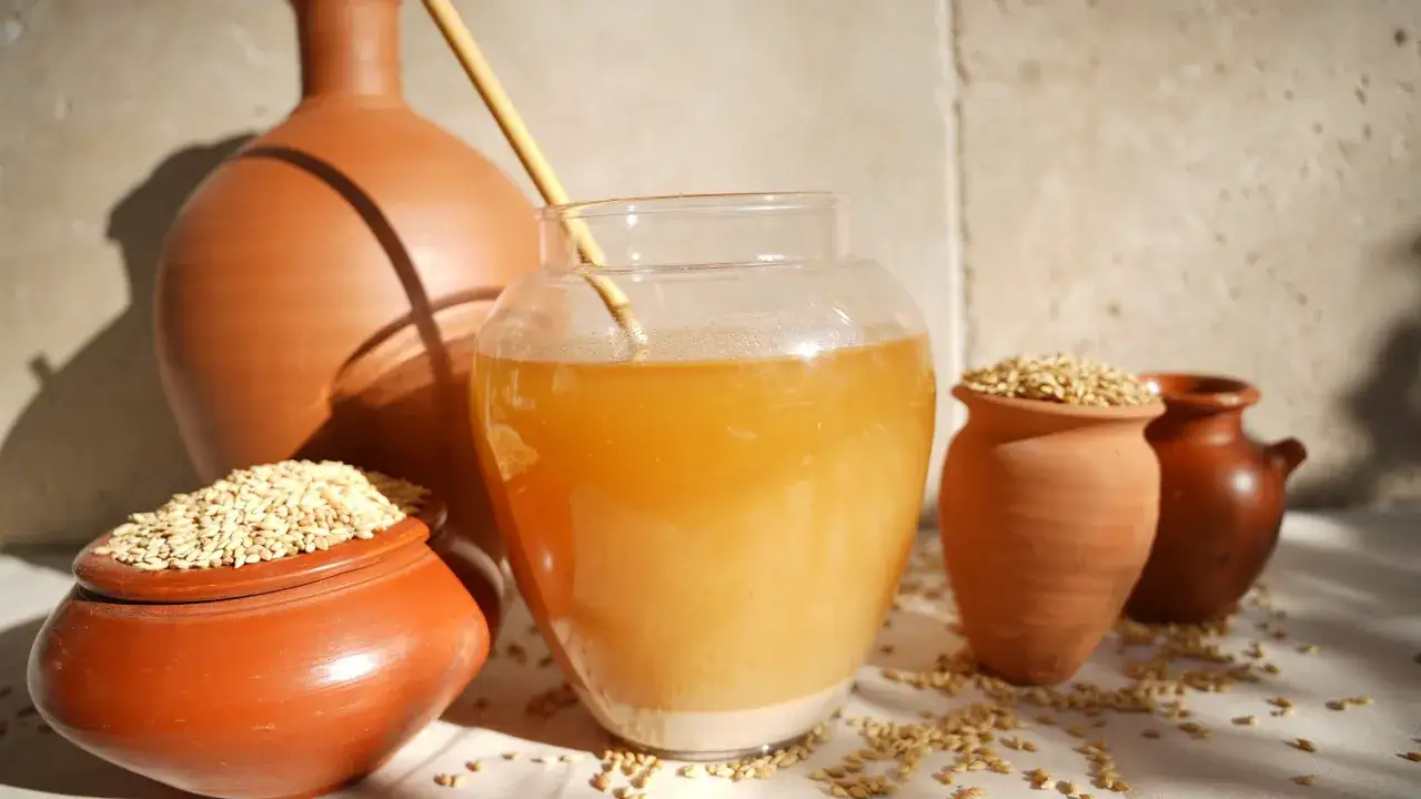 Antike Tonkrüge und ein Glas mit gelblicher Flüssigkeit, umgeben von Gerstenkörnern. Vielleicht die Antwort auf die Frage, wer hat Bier erfunden?