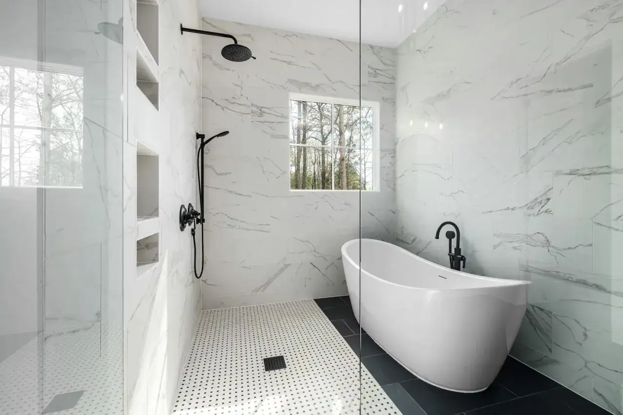 Salle de bain moderne avec baignoire &icirc;lot, douche vitr&eacute;e et carrelage marbre. La dimension carrelage des murs cr&eacute;e une ambiance luxueuse.