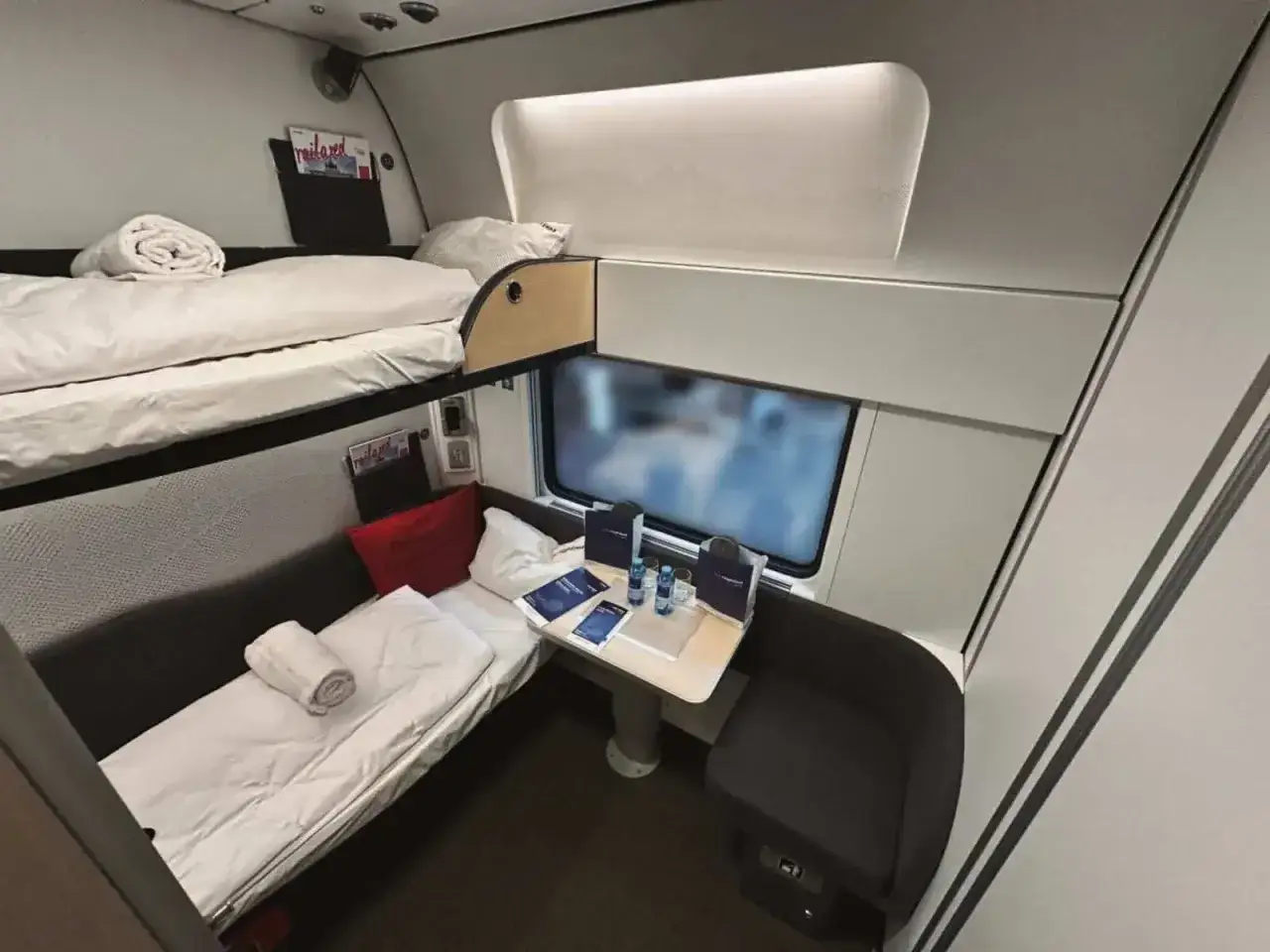 Ett mysigt tågkupé med två våningssängar, en liten sittgrupp och ett bord. Perfekt för en bekväm resa.