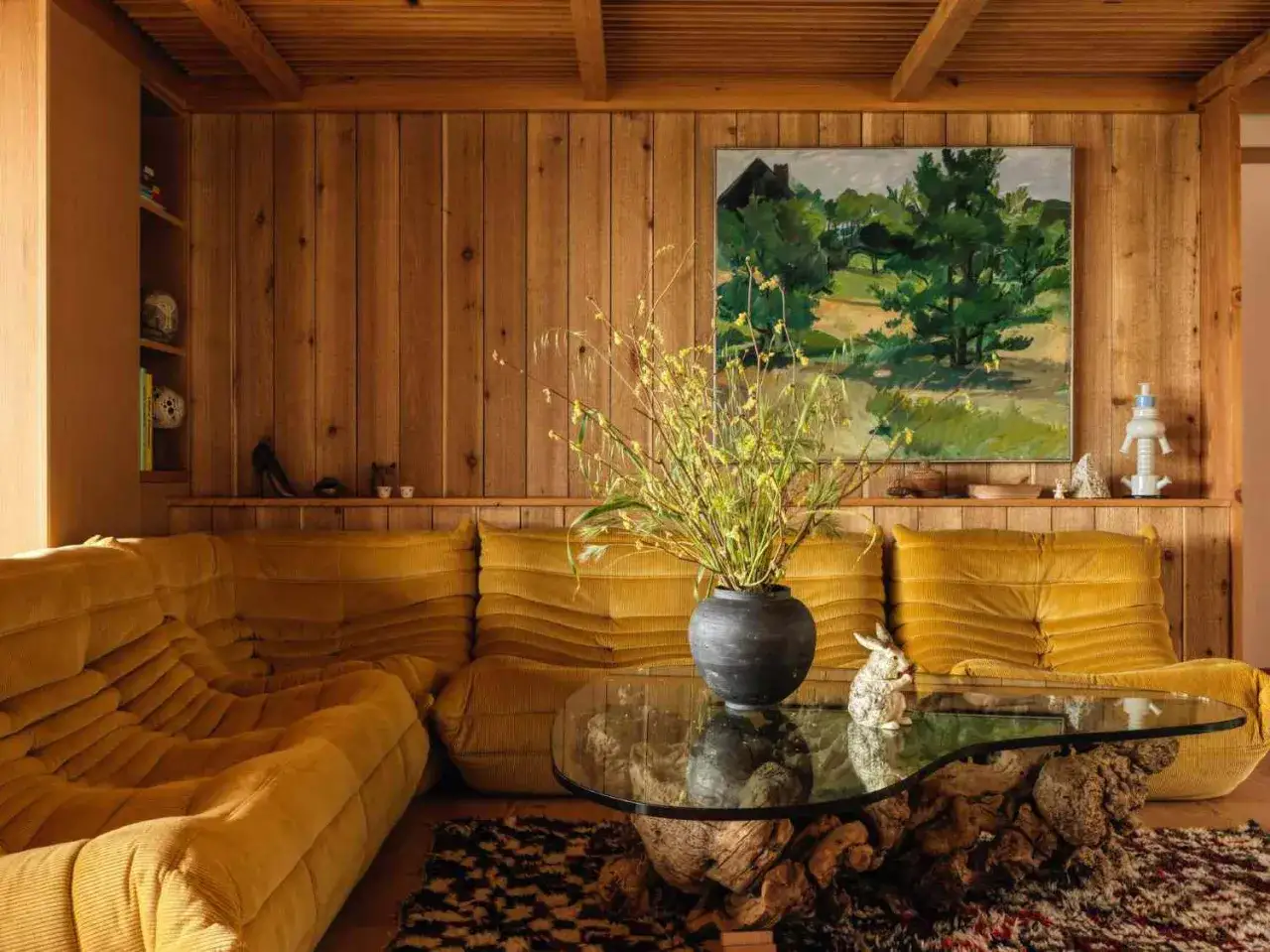 Gem&uuml;tliches Wohnzimmer im Midcentury Stil mit senfgelber Cord-Couch, Holzwand und einem rustikalen Couchtisch.