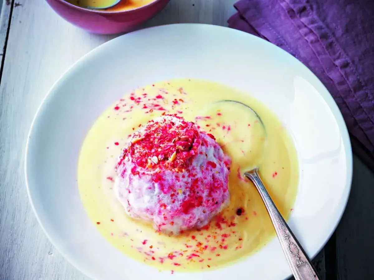 Un d&eacute;liceux dessert de oeufs &agrave; la neige, une &icirc;le flottante a&eacute;rienne saupoudr&eacute;e de fruits rouges, baignant dans une cr&egrave;me anglaise onctueuse.