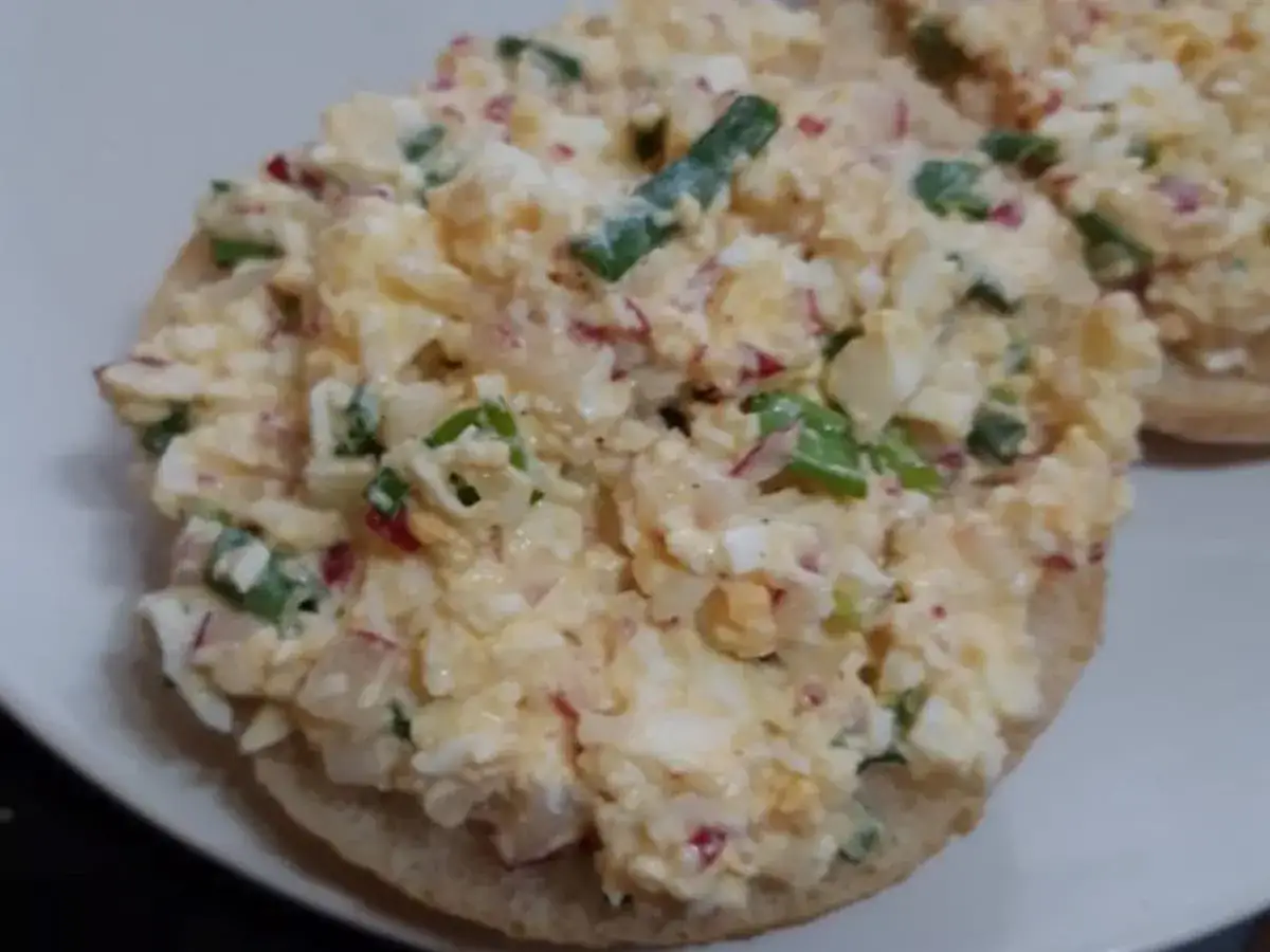 Pyszna pasta jajeczna z rzodkiewką i szczypiorkiem na bułce. Idealna na śniadanie lub przekąskę.