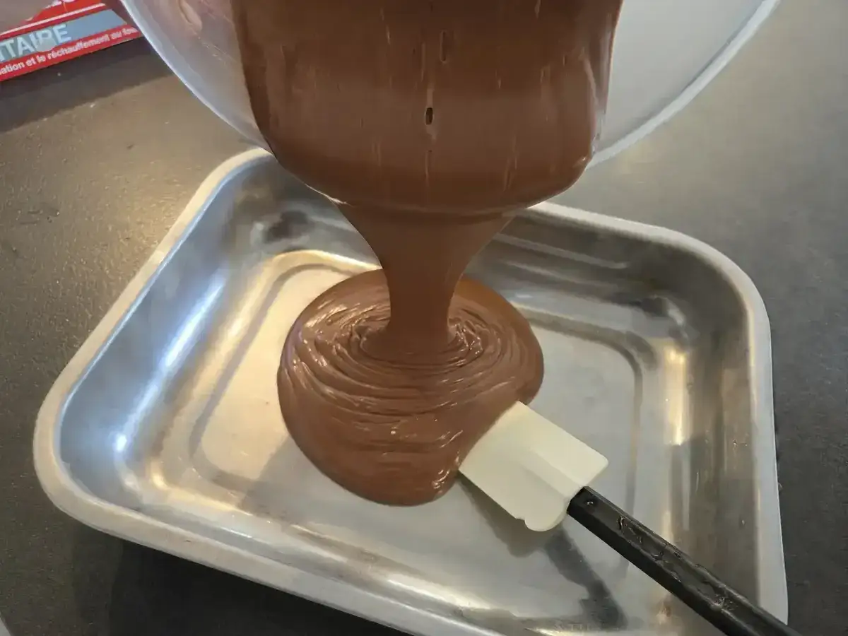 Ganache au chocolat onctueuse versée dans un plat, prête pour une délicieuse recette.