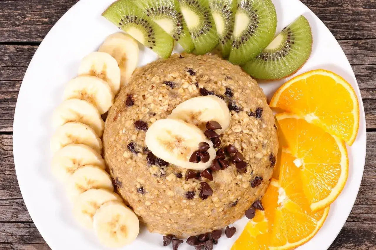 Un d&eacute;licieux bowl cake flocon d'avoine, garni de rondelles de banane, de tranches de kiwi et d'orange, parsem&eacute; de p&eacute;pites de chocolat.