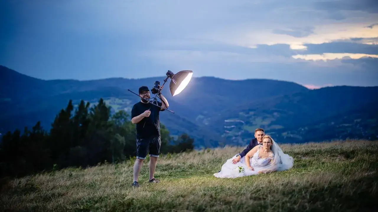 Fotograf ślubny z lampą błyskową pracuje nad sesją w górach. Ile zarabia fotograf? Zależy od jego umiejętności i zaangażowania.