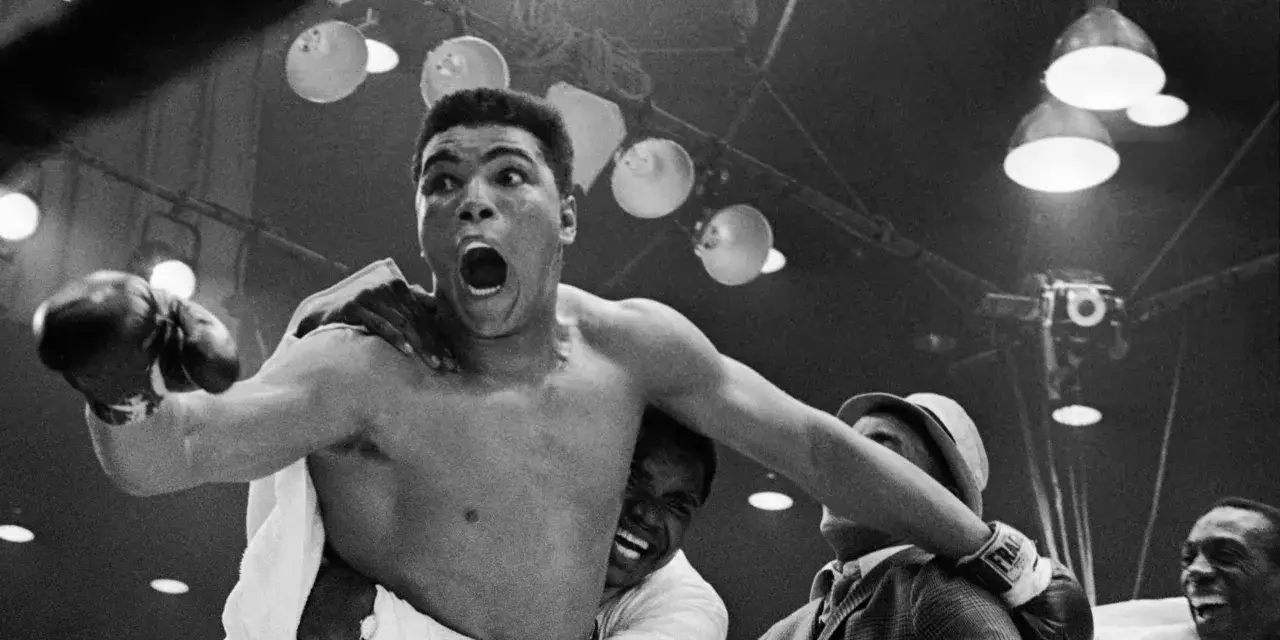 Muhammad Ali, the undisputed king of boxing, celebrates a victory with a triumphant roar, his arms raised in triumph.