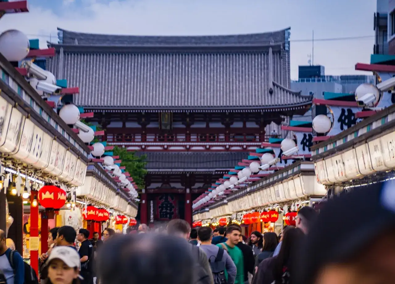 Tłum ludzi na ulicy w Japonii, z lampionami i tradycyjną architekturą. Idealne miejsce na wyjazd na własną rękę.