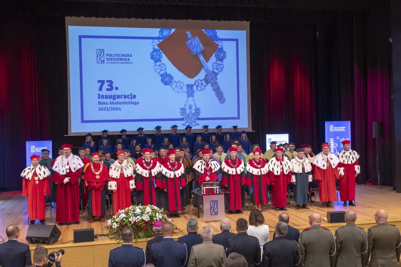 Uroczysta inauguracja roku akademickiego. Starosta w togach z innymi profesorami na scenie, podczas gdy studenci w biretach stoją za nimi.