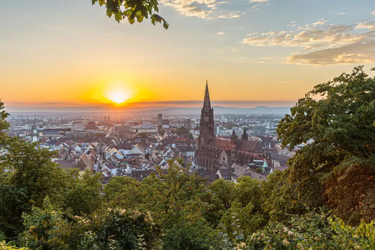 Sonnenuntergang über Freiburg. Der Münster ragt empor. Ein toller Ausblick, der zeigt, was man in Freiburg machen kann: die Stadt erkunden und genießen.