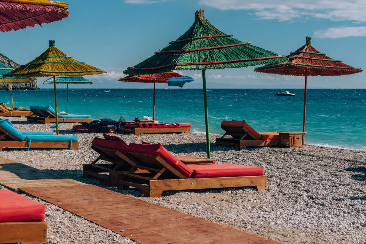 Albania, wrzesień: słoneczna plaża z leżakami i parasolami, turkusowe morze. Idealna pogoda na relaks.