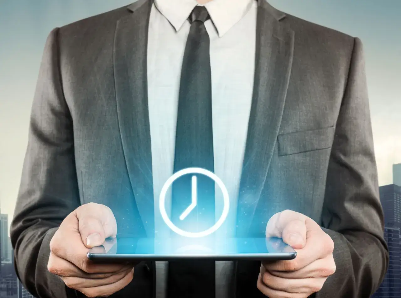 Uomo in giacca e cravatta tiene un tablet con un'icona di orologio luminoso. Il timesheet cos'&egrave;? Gestione del tempo digitale.