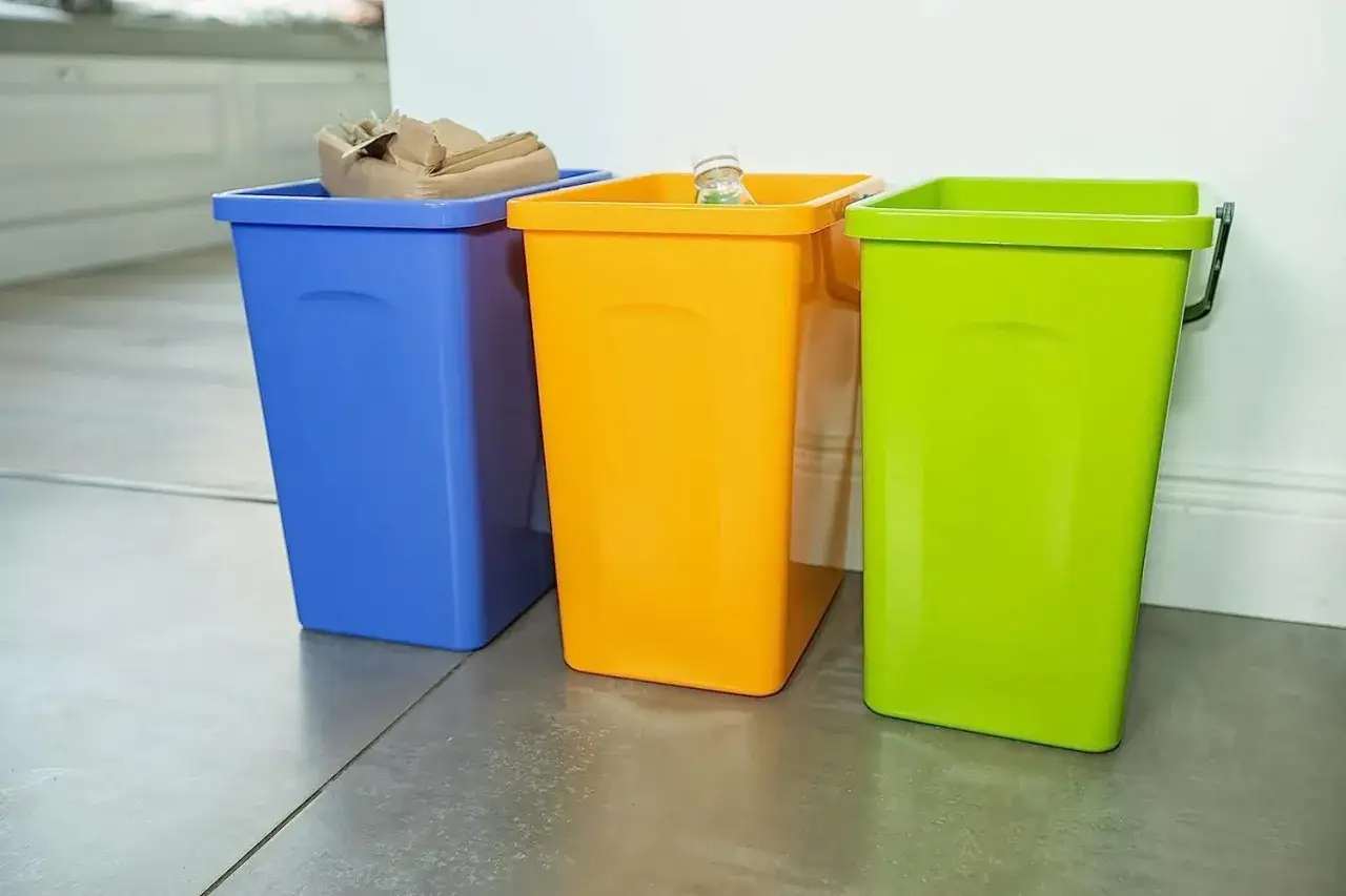 Trzy kosze na śmieci: niebieski z papierem, pomarańczowy z butelką i zielony. Jaki kolor ma plastik?