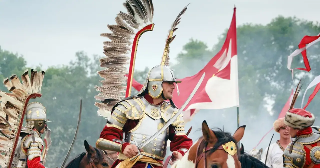 Rycerz w zbroi i z wielkimi skrzydłami na plecach, symbol polskiej husarii, na koniu, z szablą w dłoni.