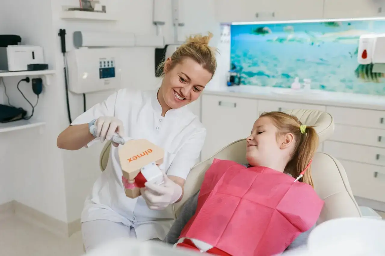Dentystka pokazuje model szczęki dziecku w gabinecie stomatologicznym.