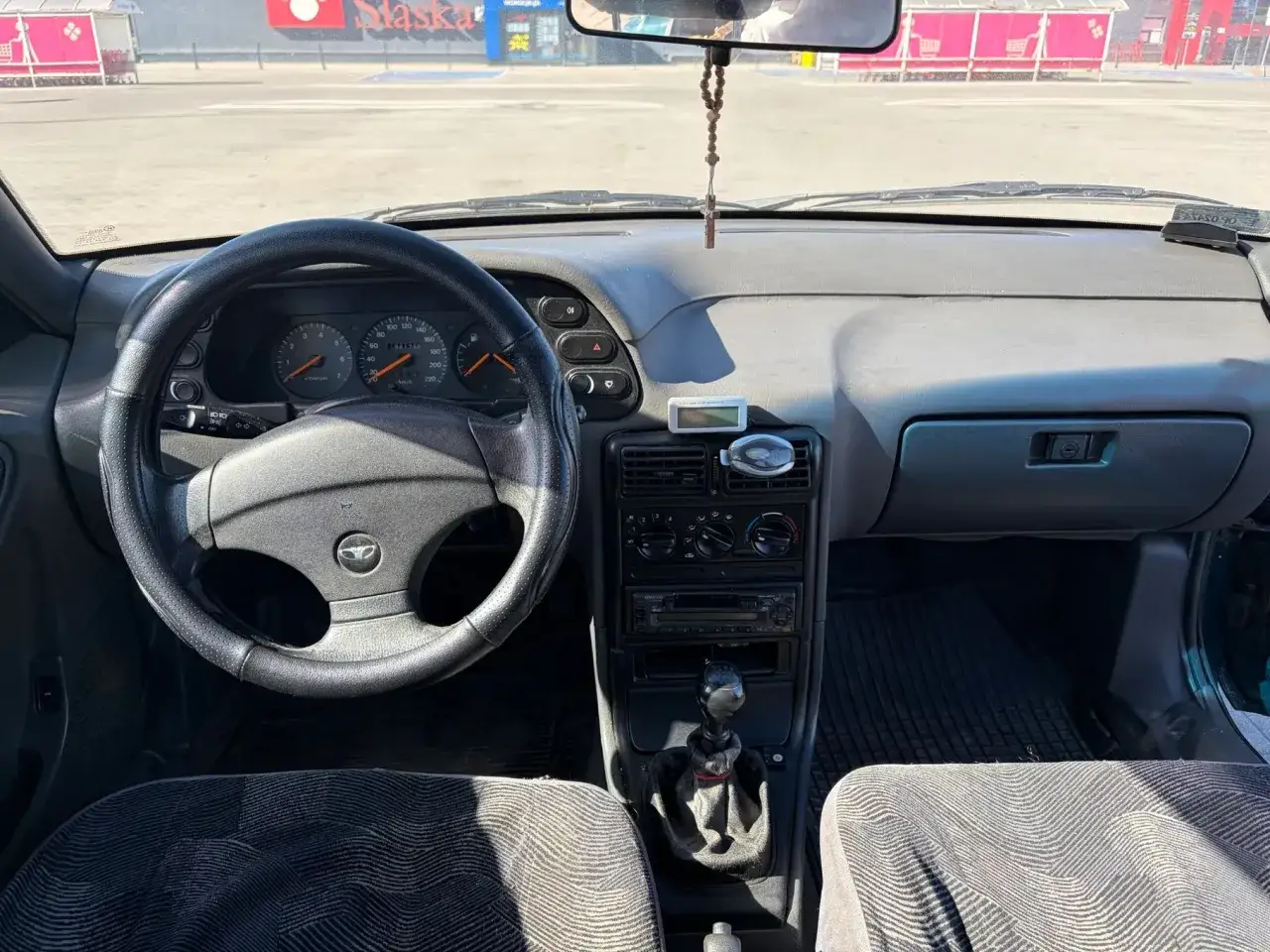 Wnętrze Daewoo Espero: kierownica, deska rozdzielcza z zegarami i radiem, dźwignia zmiany biegów.