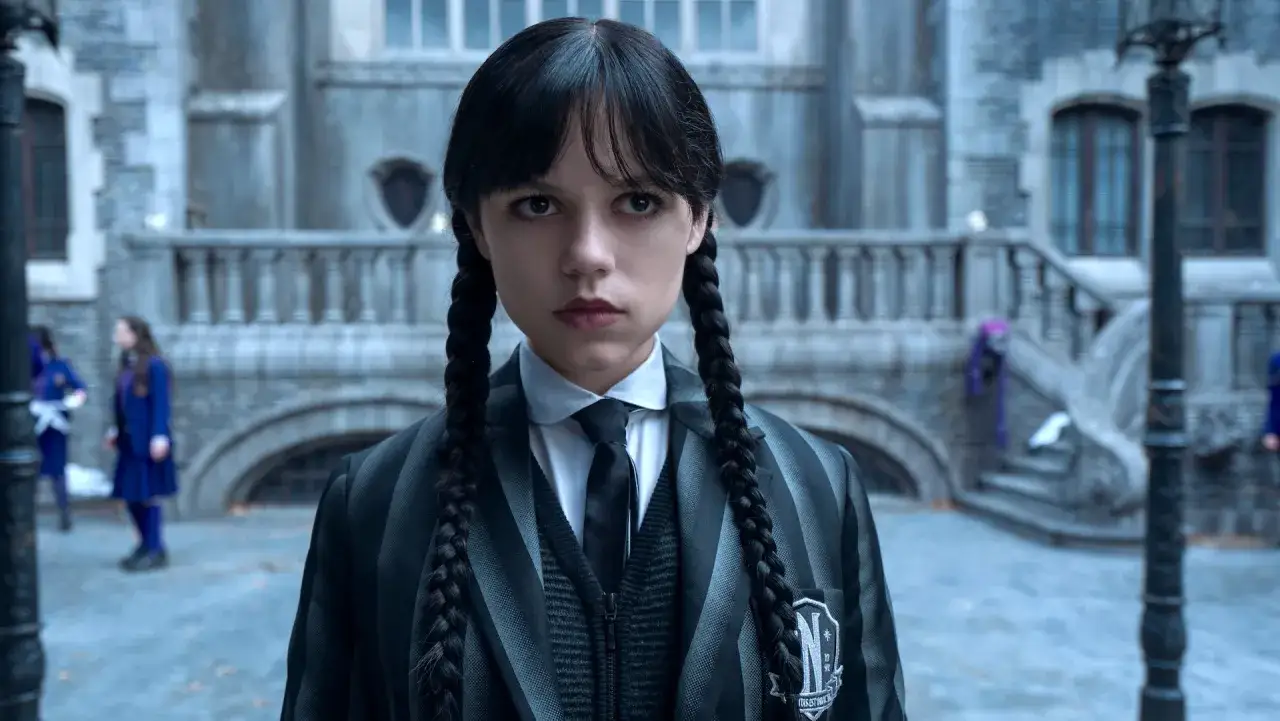 Mercredi Addams, prête pour la saison 2, arbore son uniforme emblématique devant Nevermore.