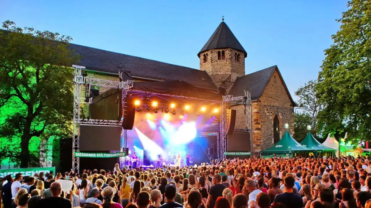 Ein gro&szlig;es Publikum feiert beim stadt ohne meer festival vor einer B&uuml;hne mit Band und Lichtern.