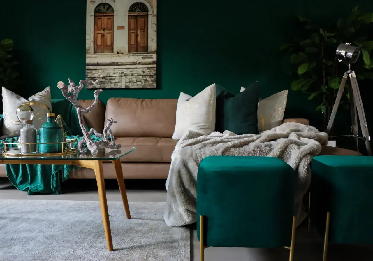 Elegancki salon z brązową kanapą, zielonymi akcentami i obrazem drzwi. Kolor piaskowy z czym łączyć? Z zielenią i złotem dla luksusowego efektu.