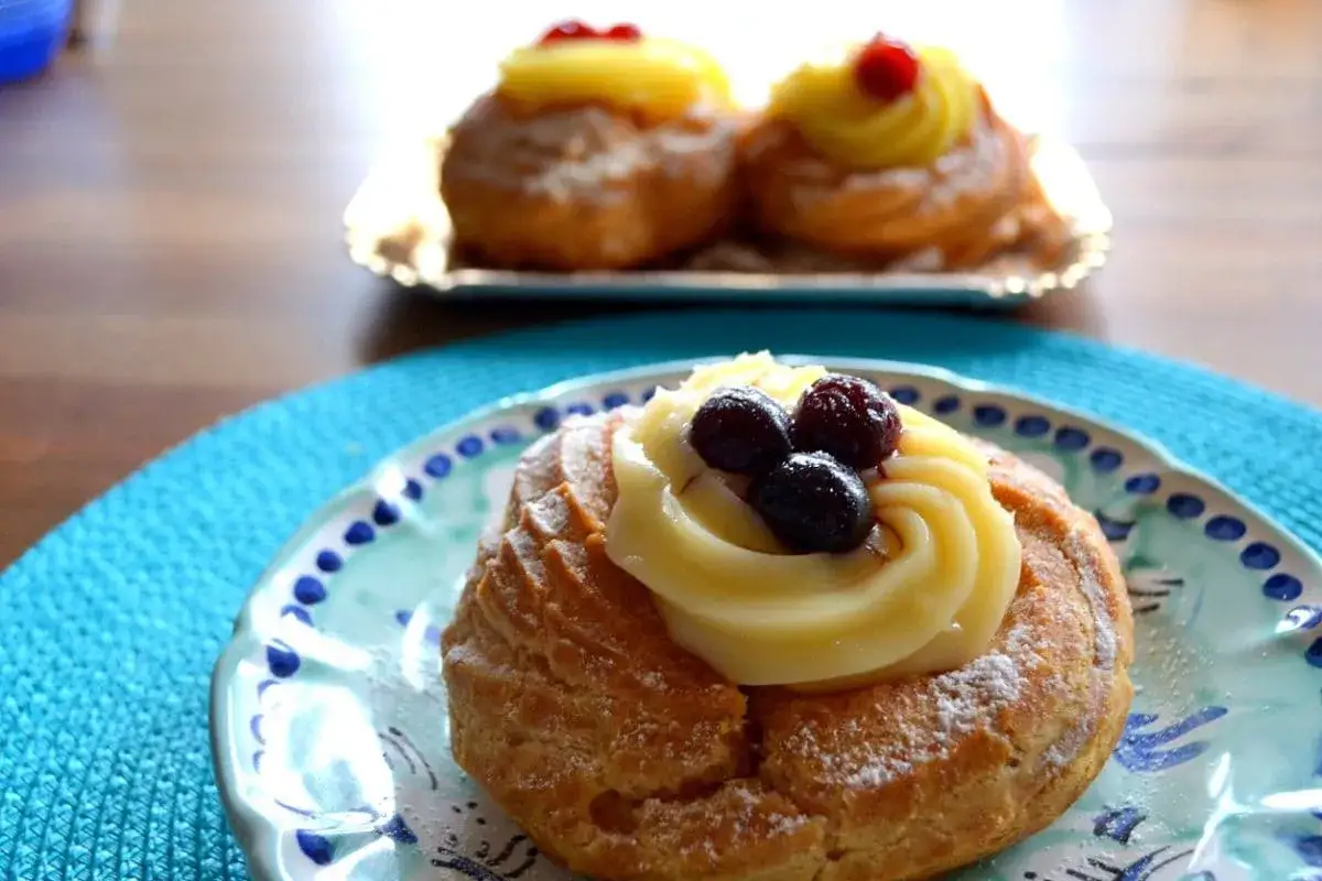 Zeppole napoletane, un delizioso cibo napoletano, con crema pasticcera e frutti di bosco su un piatto decorato.