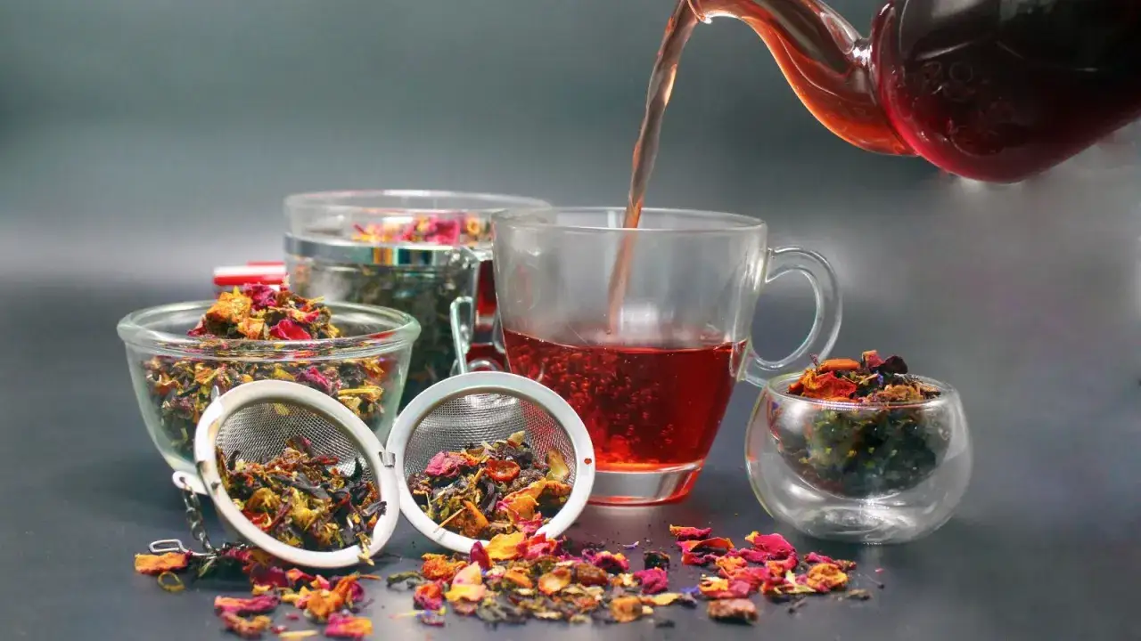 Napar z rooibos zielony i czerwony w szklance, obok miseczki z suszem i zaparzacze.