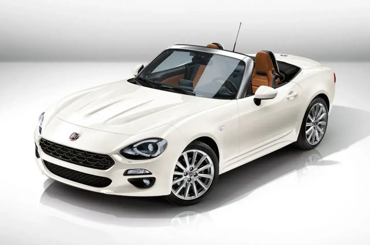 Biały Fiat Spider z brązową skórzaną tapicerką, gotowy na letnią przejażdżkę.