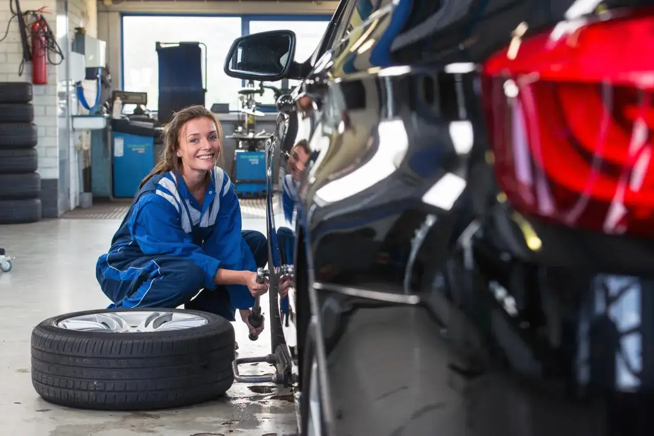 Meccanica sorridente effettua il cambio gomme estive alla sua auto in officina.