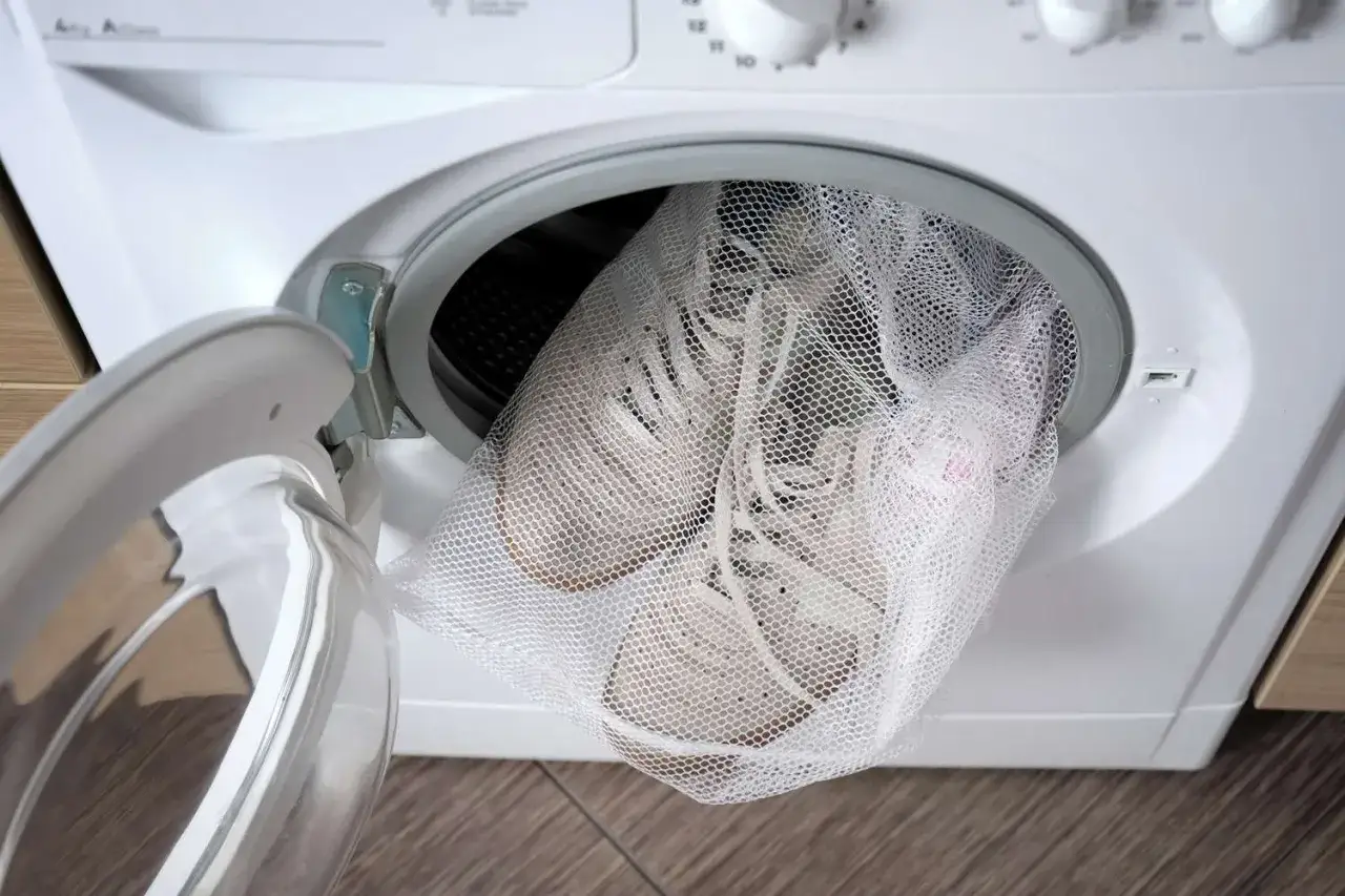 Scarpe da ginnastica in un sacchetto a rete pronte per essere lavate in lavatrice. Ecco come lavare scarpe da ginnastica in lavatrice per farle tornare come nuove.