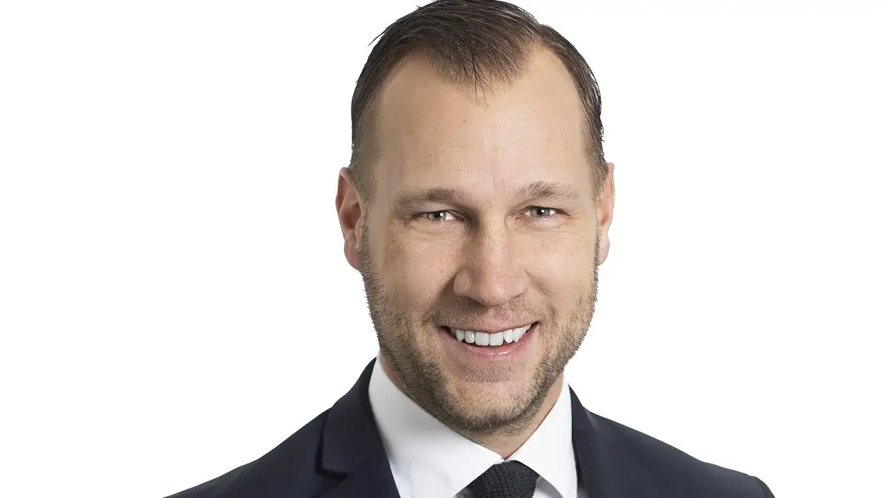 Portr&auml;tt av Viktor Svensson i kostym, med ett v&auml;nligt leende och blicken riktad mot kameran.