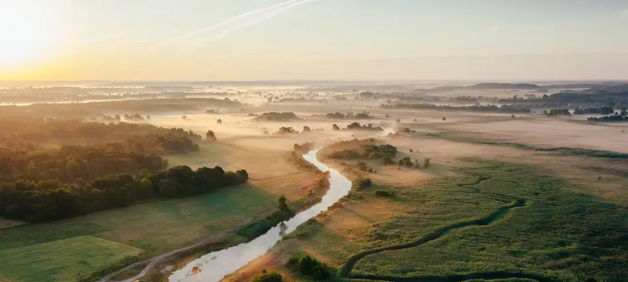 Mglisty poranek nad Narwią. Kręta rzeka, lasy i pola tworzą malownicze krajobrazy, które są głównymi atrakcjami Narwiańskiego Parku Narodowego.