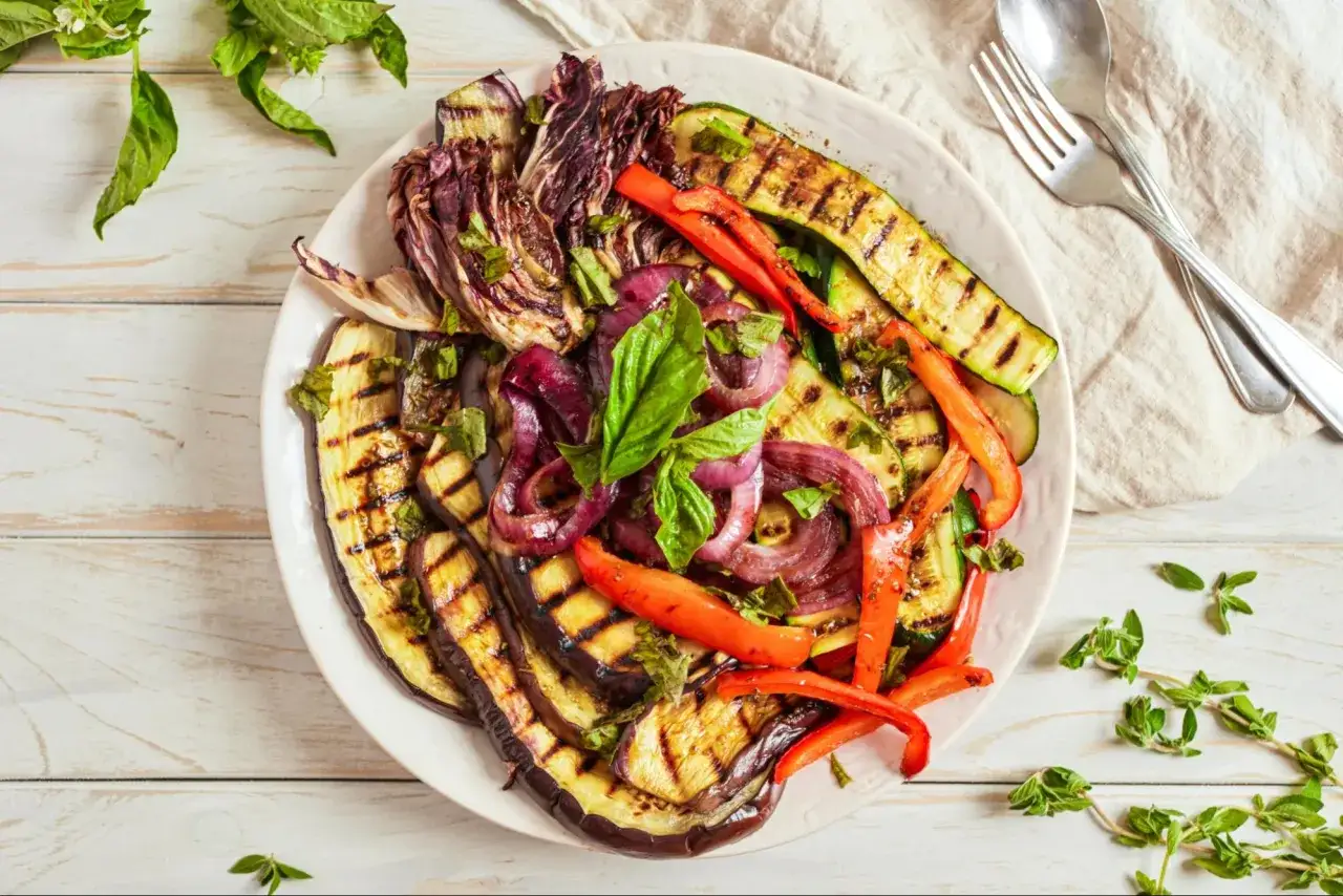 Assiette de l&eacute;gumes grill&eacute;s, un d&eacute;lice de barbecue italien : aubergines, courgettes, poivrons rouges, oignons et radicchio, parsem&eacute;s de basilic frais.