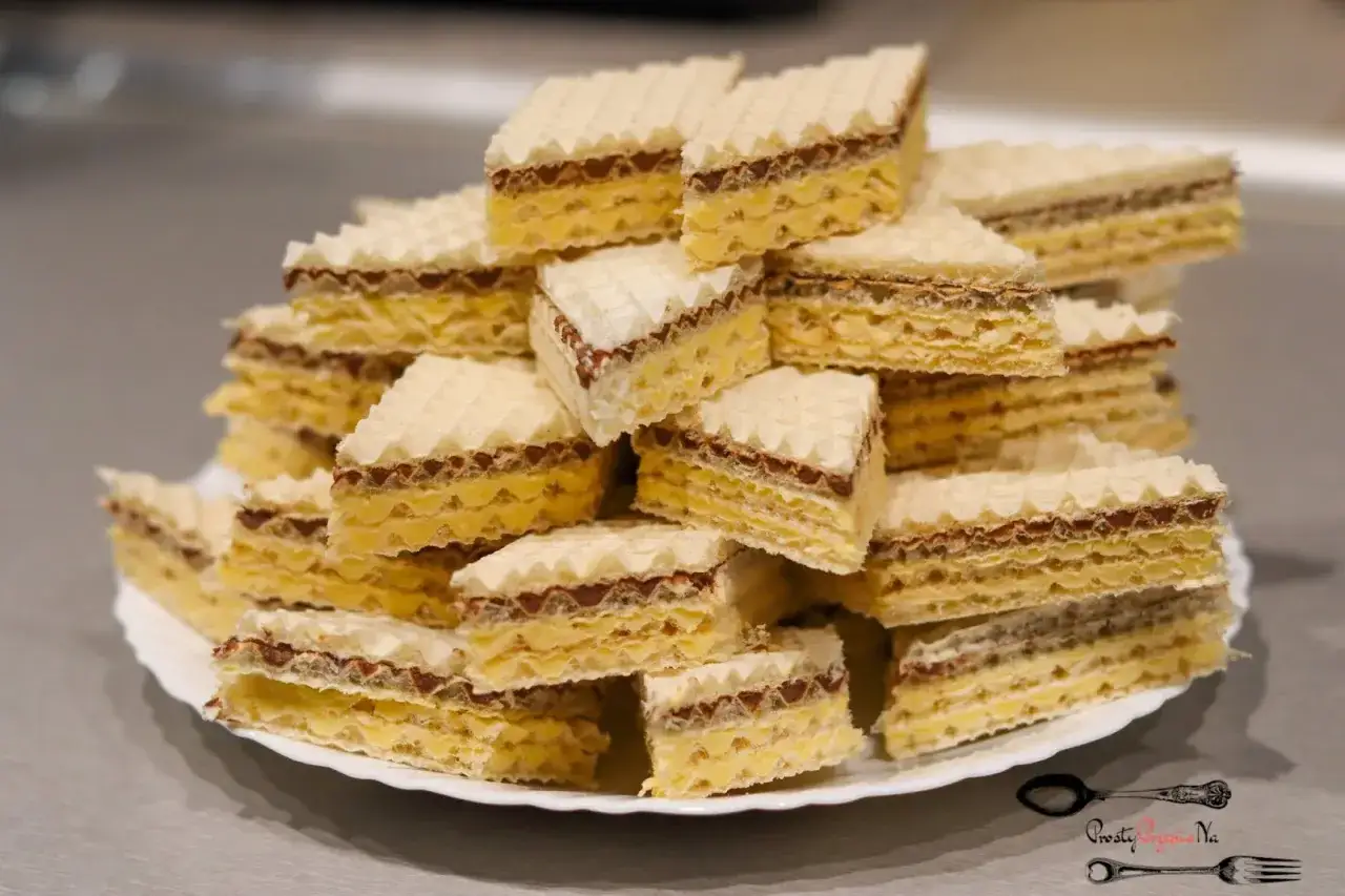 Stary przepis na wafle, ułożone na talerzu. Chrupiące wafle przełożone kremem czekoladowym i żółtym nadzieniem.
