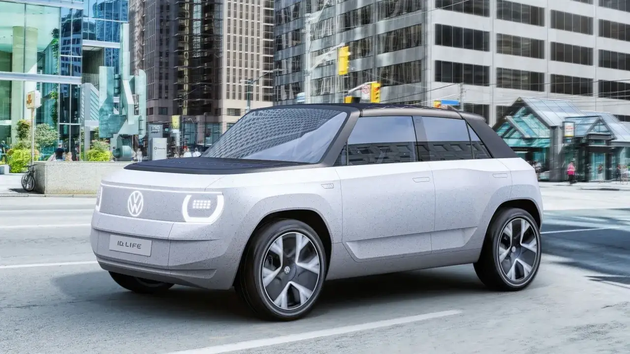 El Volkswagen ID. LIFE, un concepto de coche eléctrico urbano, circula por una calle de ciudad con edificios modernos de fondo.