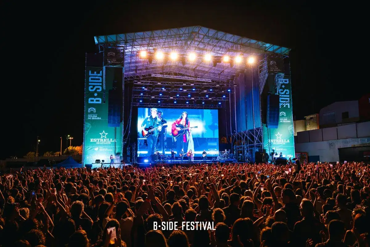 Gran concierto en el B-Side Festival, con una multitud vibrante y artistas tocando en el escenario principal, todo esto en Molina de Segura.