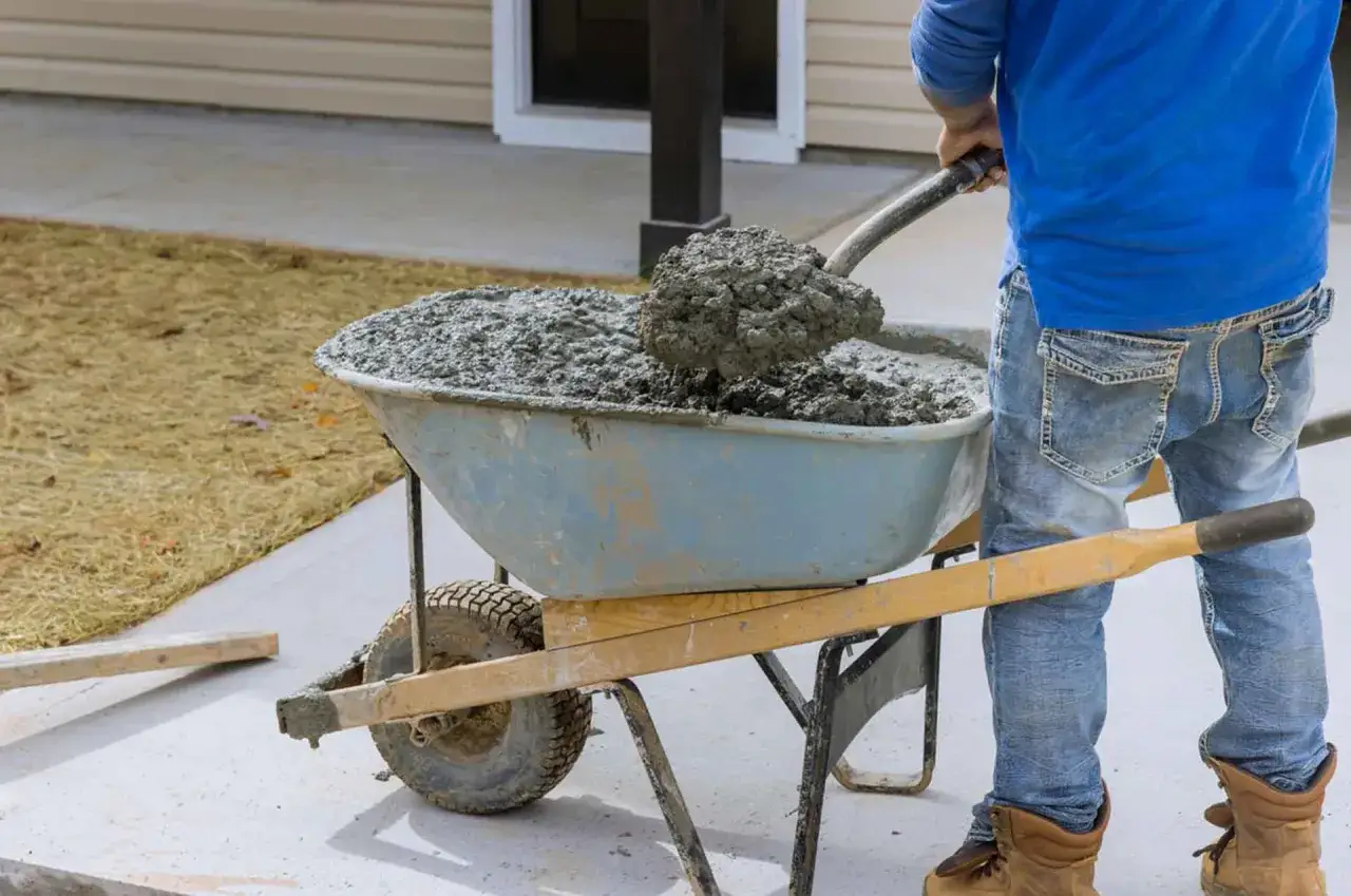 Un ouvrier charge du b&eacute;ton frais dans une brouette. Le temps pour couler 1m3 b&eacute;ton seul est une t&acirc;che exigeante.