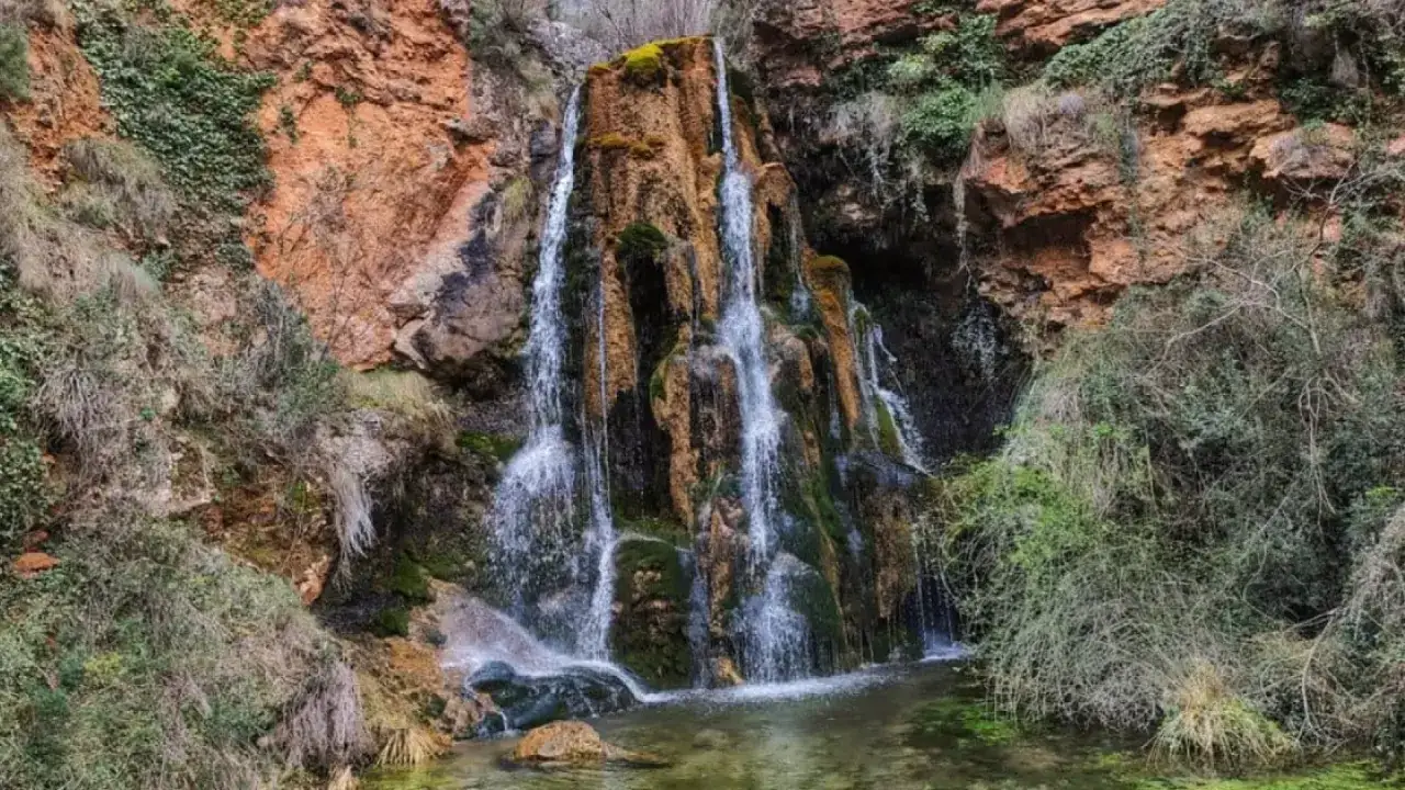 Cascadas en Albacete, un espect&aacute;culo natural de agua cayendo por rocas rojizas y vegetaci&oacute;n exuberante.