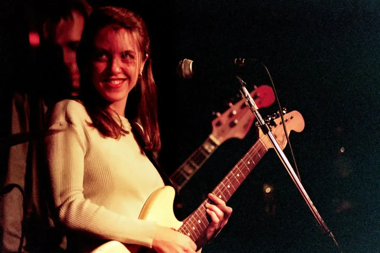Liz Phair souriante, guitare &agrave; la main, sur sc&egrave;ne.