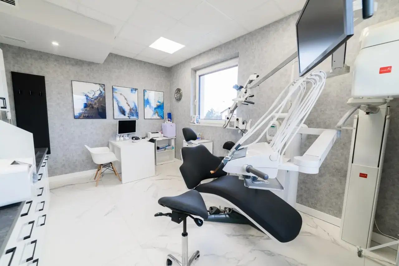 Nowoczesny gabinet stomatologiczny z fotelem dentystycznym i sprzętem medycznym.
