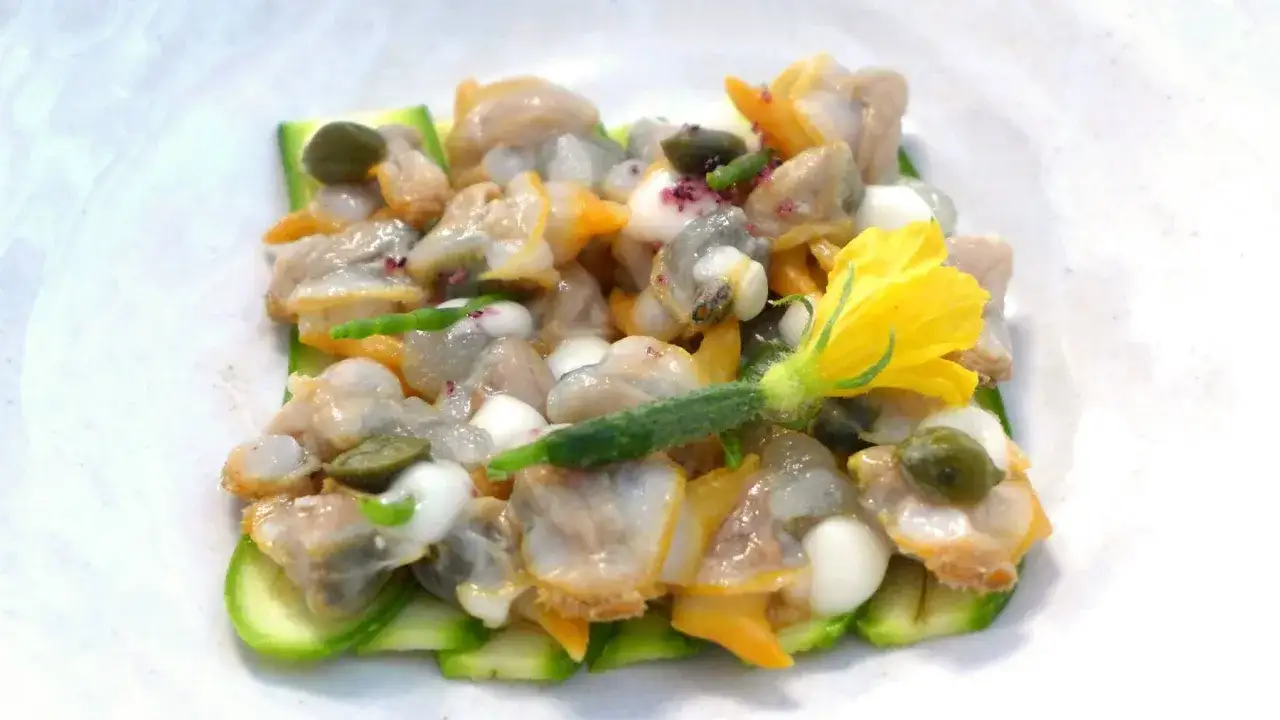 Delicioso ceviche de berberechos con pepino, alcaparras y una flor amarilla.