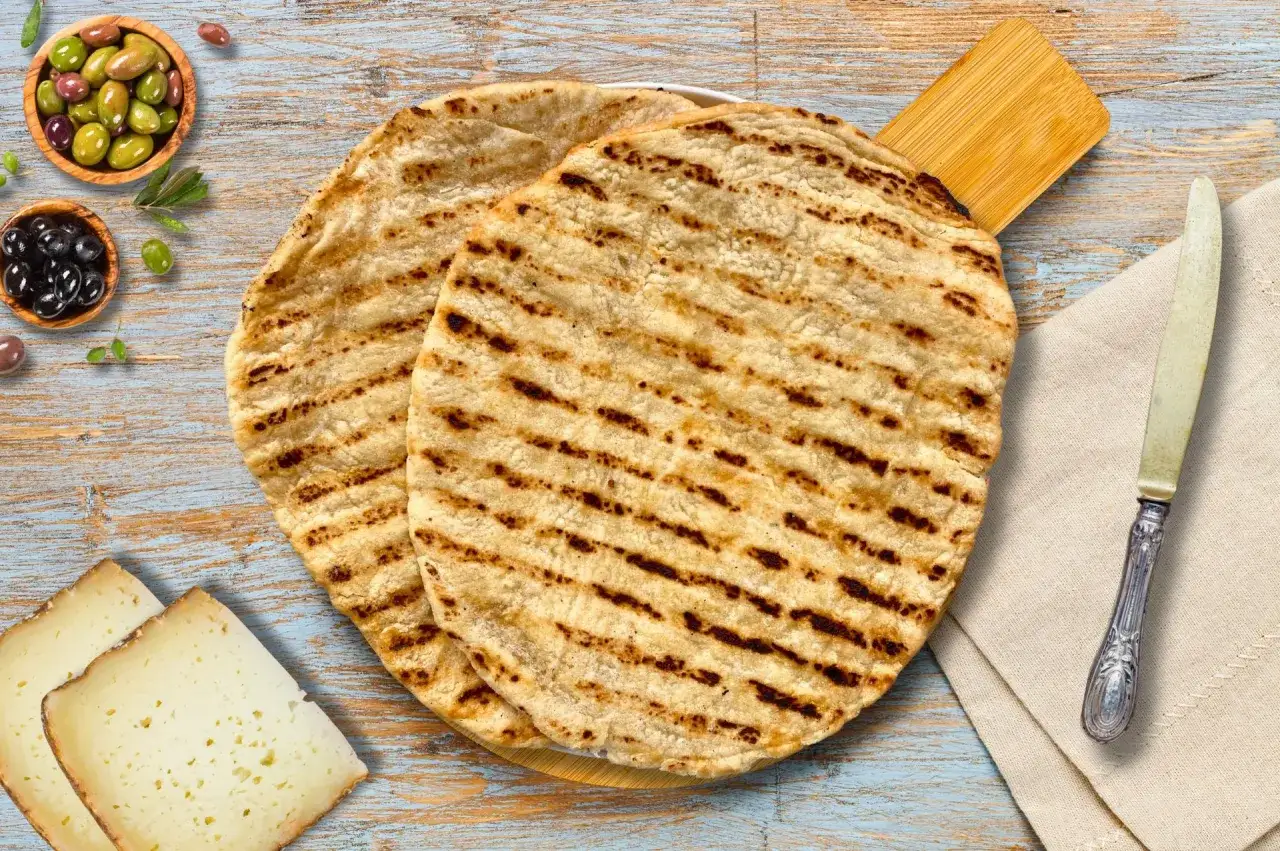 Due focacce grigliate, pronte per una ricetta crescia con formaggio e olive.