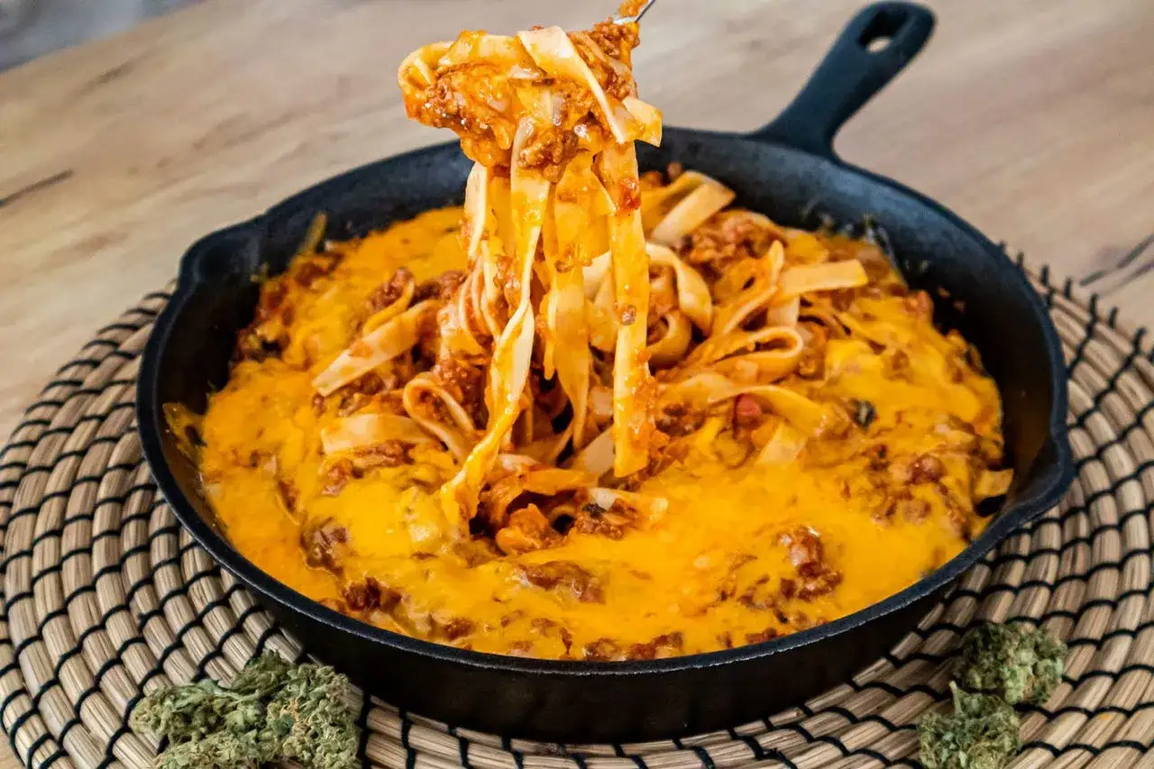 Tagliatelle al ragu z ciągnącym serem w żeliwnej patelni. Pyszne danie, które rozpływa się w ustach.