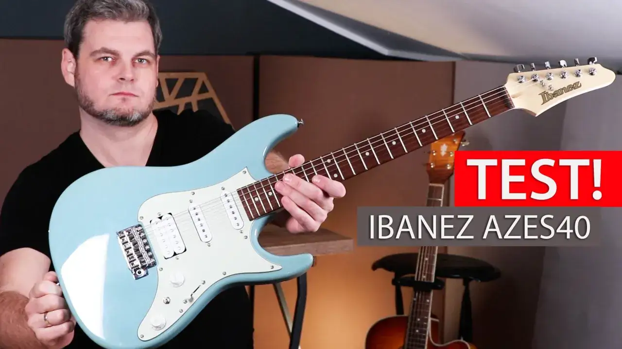 Mężczyzna prezentuje jasnoniebieską gitarę elektryczną Ibanez AZES40, gotowy do gry.