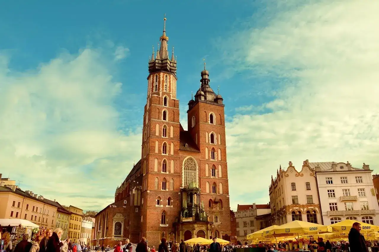 Bazylika Mariacka w Krakowie na tle błękitnego nieba z chmurami.