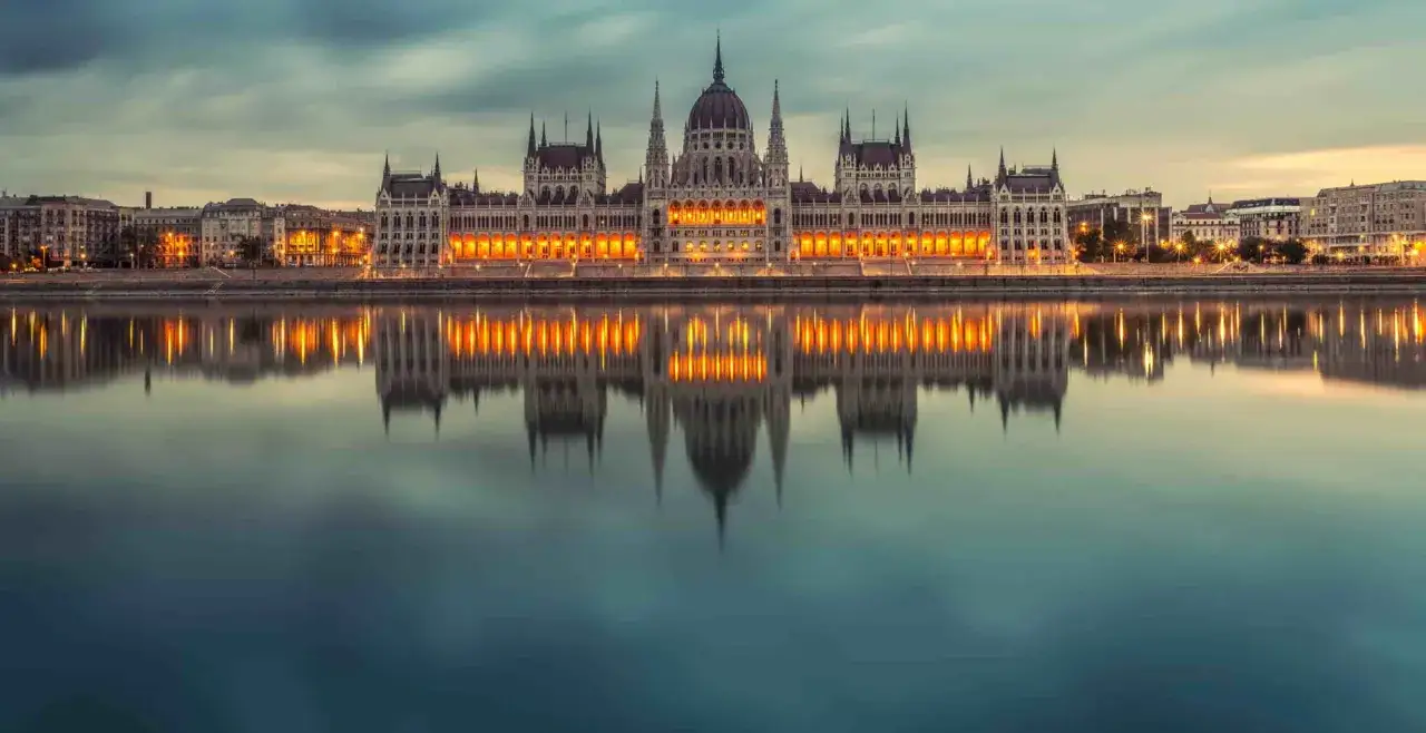 Das Parlamentsgebäude in Budapest spiegelt sich im Wasser. Eine Reise von Hamburg nach Budapest mit dem Zug ist eine tolle Idee!