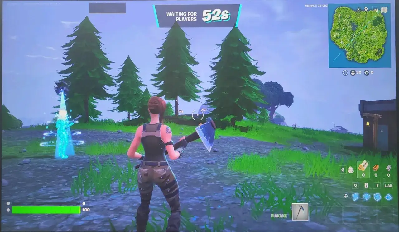 Postać w grze, podobnej do Fortnite, czeka na rozpoczęcie meczu. W tle widać drzewa i mapę.