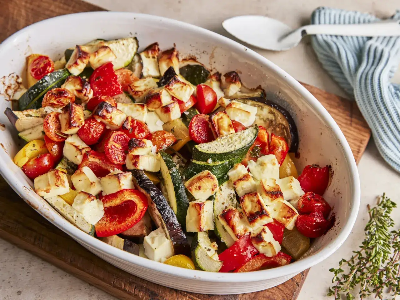 Gebackener Feta mit mediterranem Gem&uuml;se wie Tomaten, Zucchini und Paprika in einer Auflaufform.