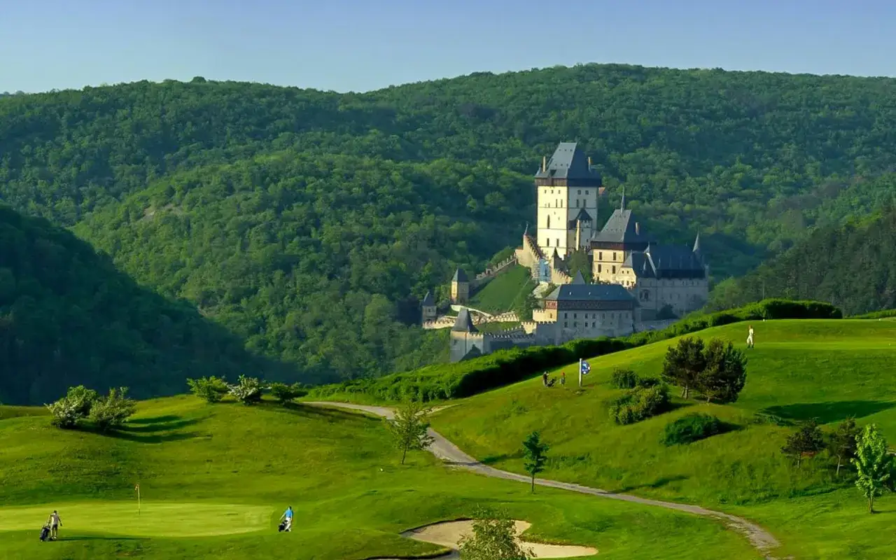 Castillo Karl&scaron;tejn, ideal para excursiones en Prague, rodeado de colinas verdes y un campo de golf.