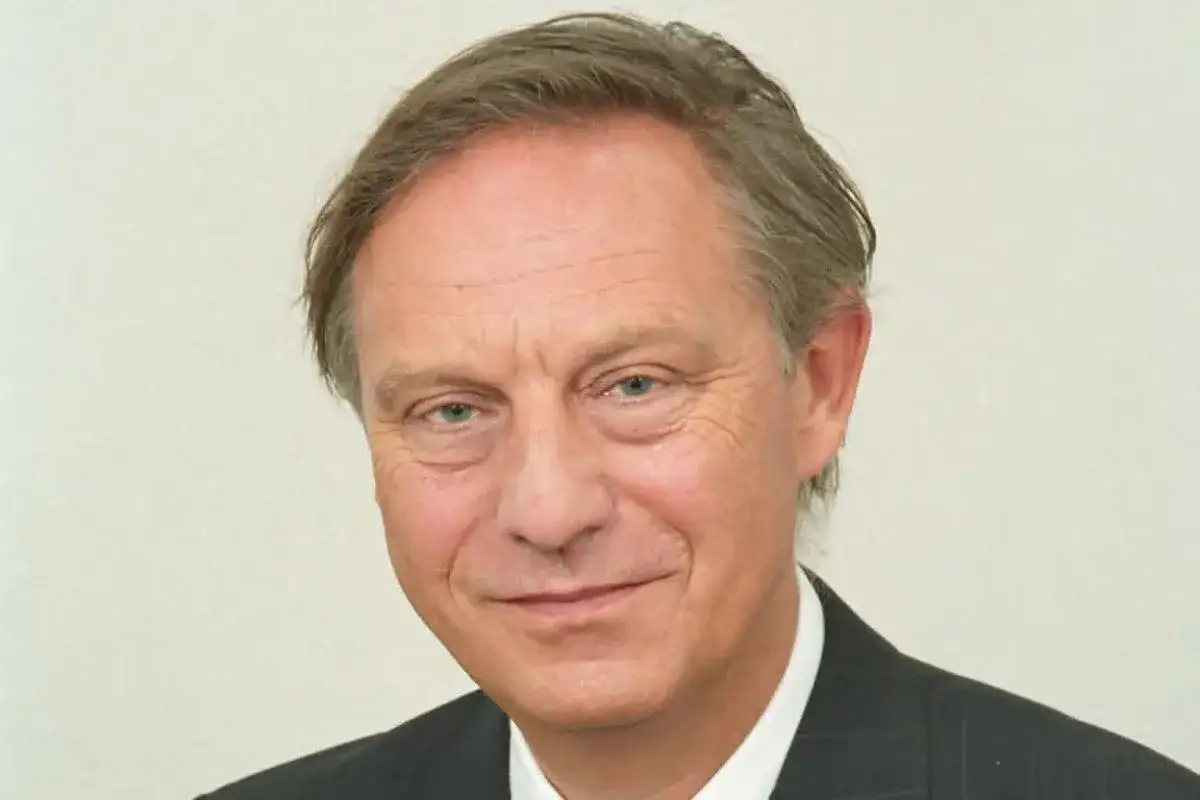 Uśmiechnięty mężczyzna, Andrzej Mularczyk, w garniturze i białej koszuli, z siwiejącymi włosami.